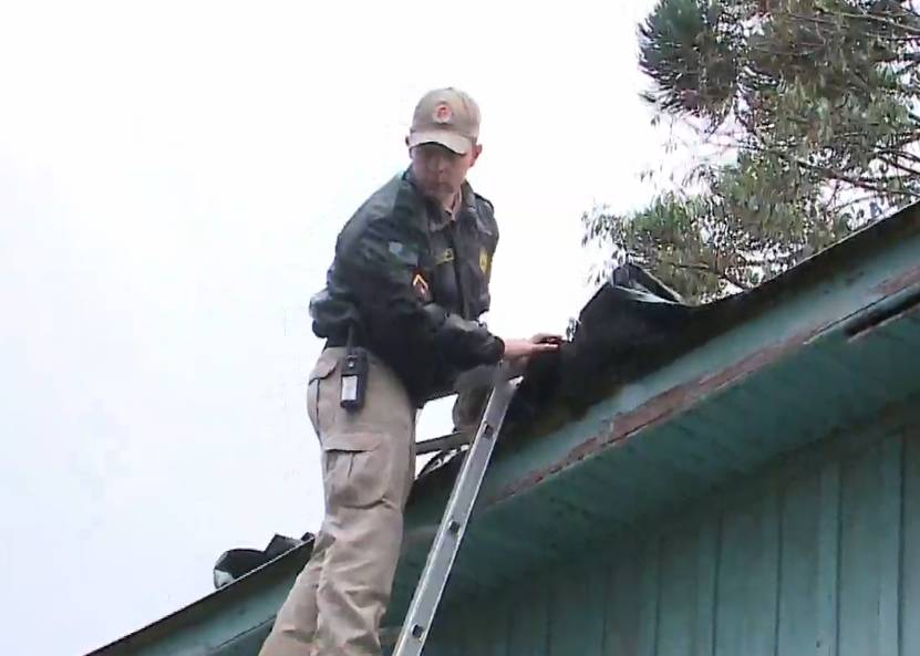 Agentes da Defesa Civil ajudam moradores e colocar lonas nas casas. 